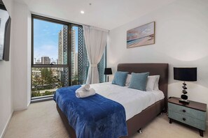 Een hotelkamer met een groot bed, een nachtkastje, een raam met gordijnen en een schilderij aan de muur.