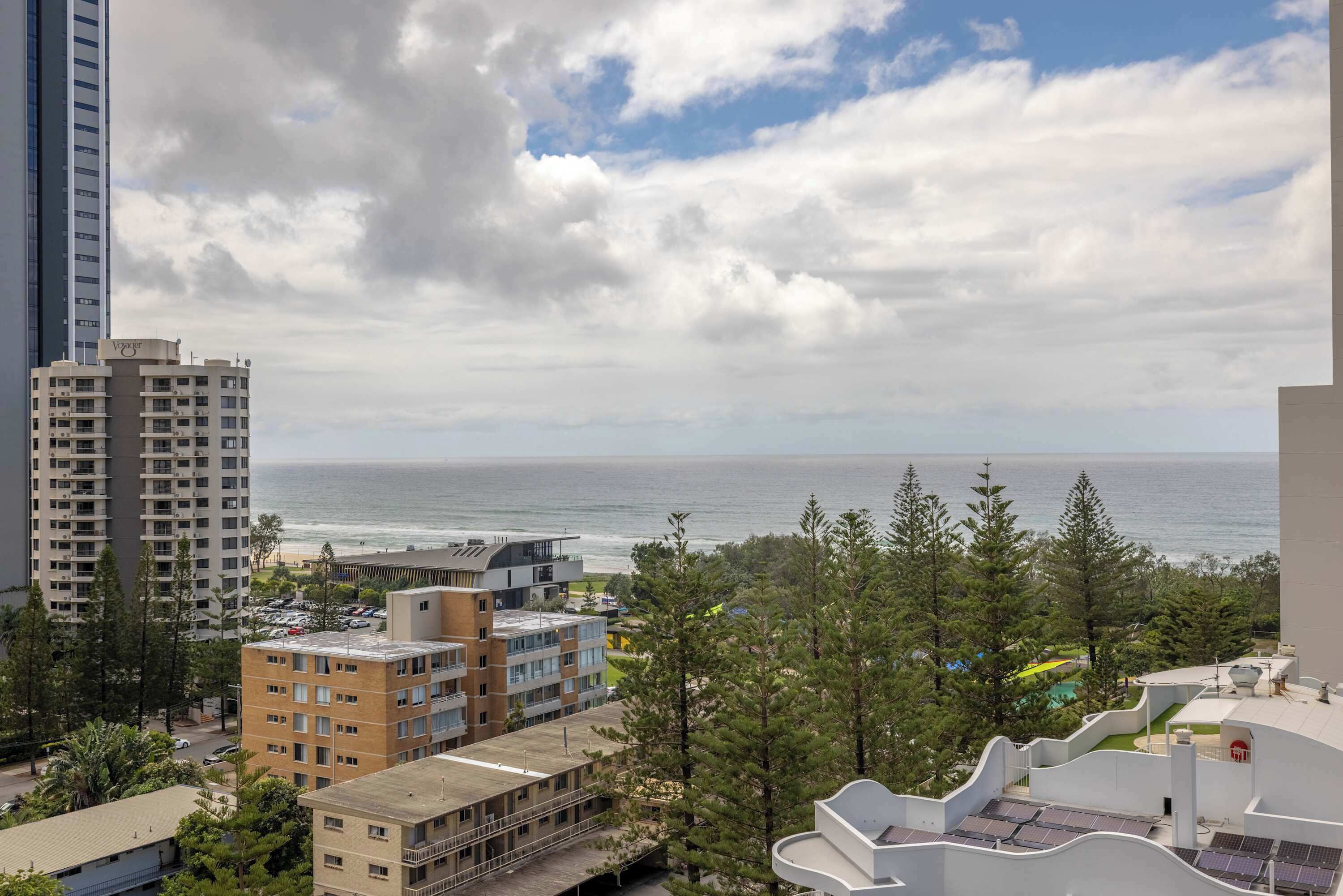 A coastal cityscape with high-rise buildings, a beach, and a view of the ocean.