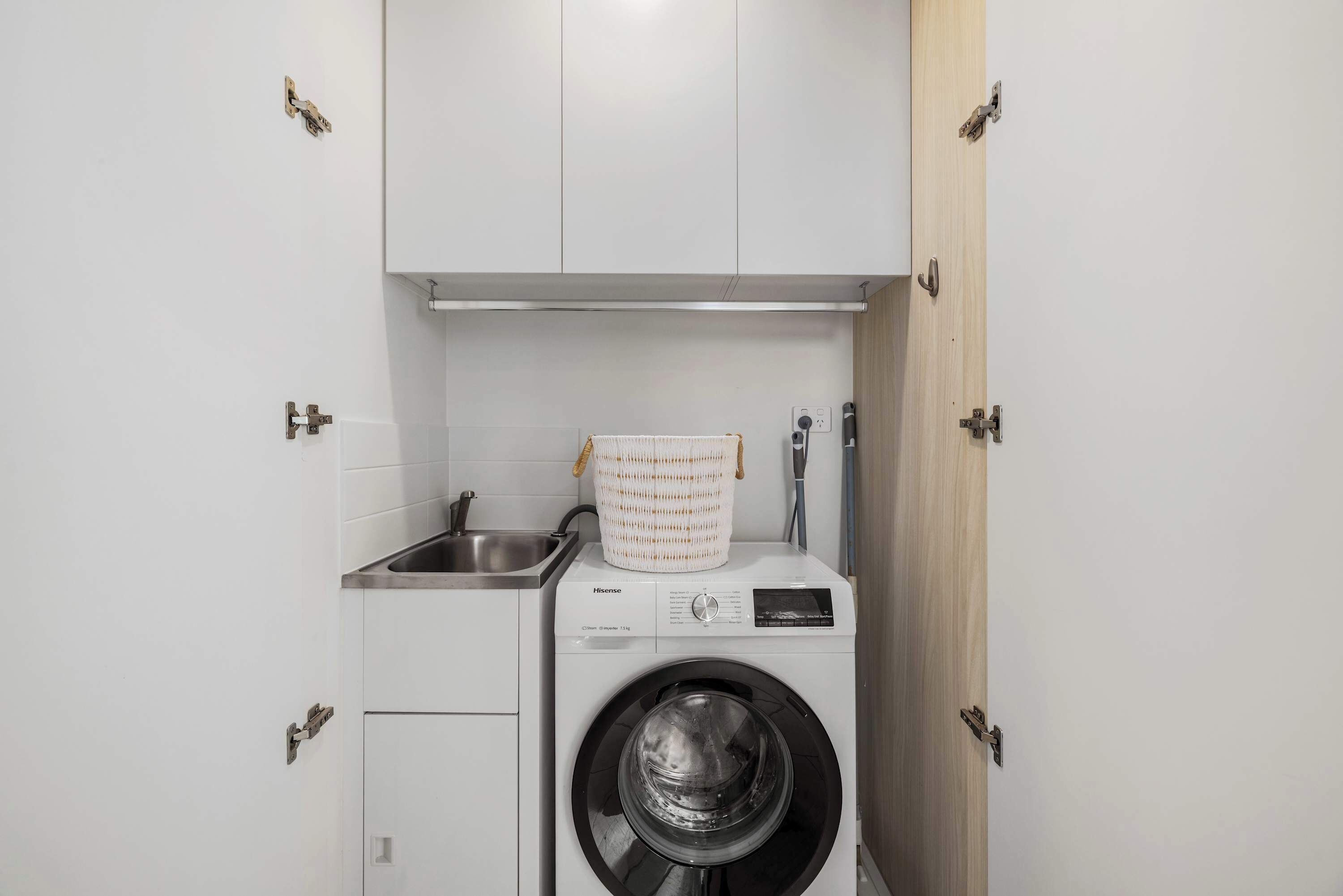 Ein kleiner Waschbereich mit Waschmaschine, Spüle und Schrank.
