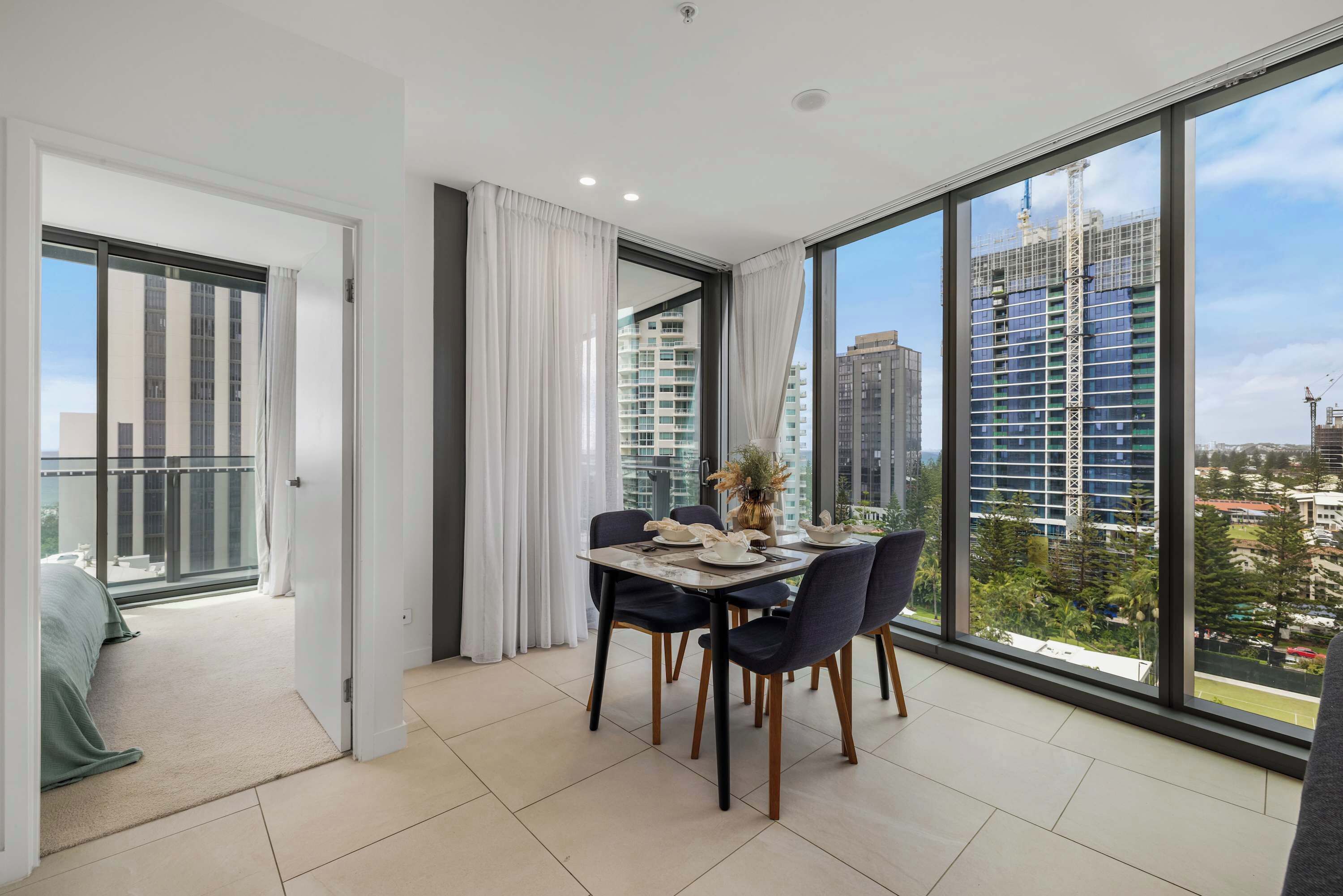 Een modern appartement met een eethoek, grote ramen en een balkon.