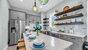 A modern kitchen with a central island, stainless steel appliances, and wooden shelves. - 🦩Book Me Baby! Seaglass in Santa Rosa Beach  ~ Golf Cart Included🦩 (Santa Rosa Beach)