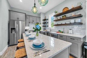 Una cocina moderna con una isla central, electrodomésticos de acero inoxidable y estantes de madera.