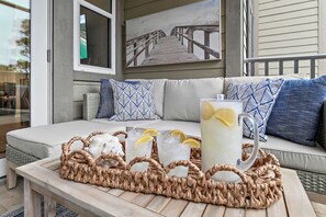 A wicker tray with drinks and a pitcher on a table, a sofa with patterned cushions, and a painting of a pier. - NEW Rental in Seagrove on 30A Close to Beach! (Santa Rosa Beach)