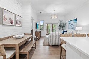 A spacious living area with a wooden dining table, benches, a sofa, and a TV mounted on the wall. - NEW Rental in Seagrove on 30A Close to Beach! (Santa Rosa Beach)