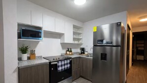 Een moderne keuken met witte kasten, een roestvrijstalen koelkast, een magnetron en een oven.