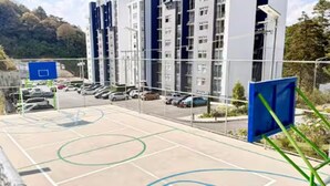 Een parkeerplaats met meerdere auto's, een basketbalveld en een gebouw met een modern ontwerp.