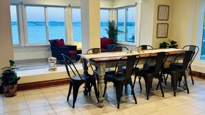 Een eethoek met uitzicht op het water, een tafel met stoelen en potplanten.