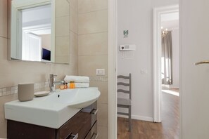 Une salle de bain moderne avec un lavabo blanc, un miroir et un porte-serviettes.