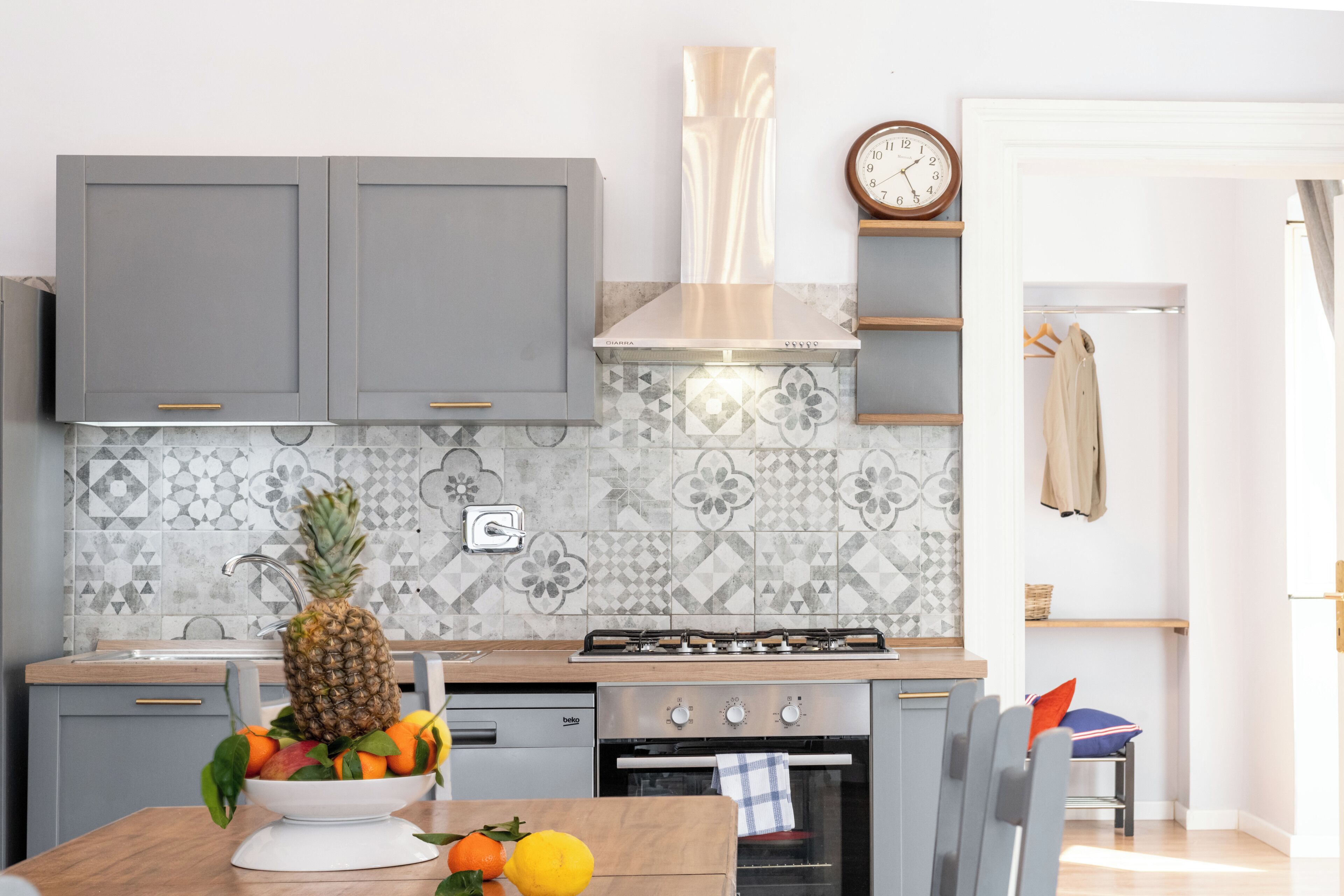 Una cocina moderna con armarios grises, una estufa a gas y un salpicadero de azulejos.