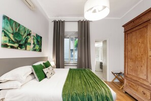 Une chambre à coucher avec un lit, des oreillers verts, une couverture verte, une armoire en bois et un tableau accroché au mur.
