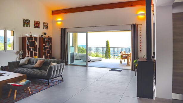 En moderne stue med sofa, spisebord og balkon med udsigt.