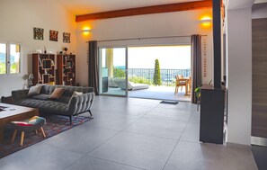 A modern living room with a sofa, a dining table, and a balcony with a view. - Gorgeous home in Speracedes with WiFi (Speracedes)