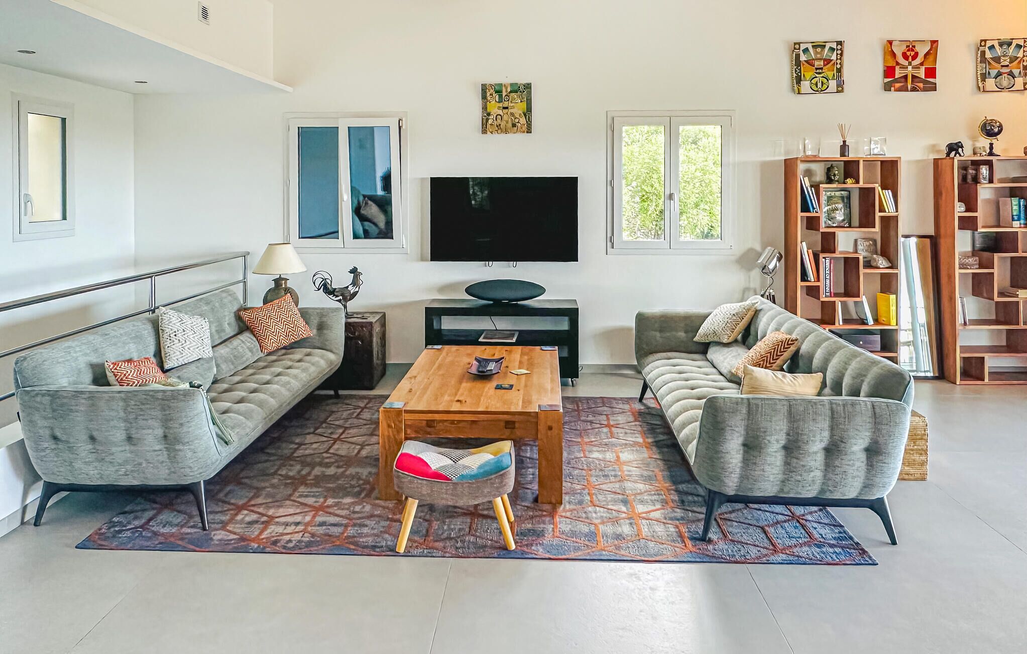 Uma sala de estar moderna com um sofá, uma mesa de centro, uma televisão e uma estante de livros.