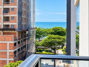 Un edificio alto con vista al mar, un balcón y un cielo despejado.