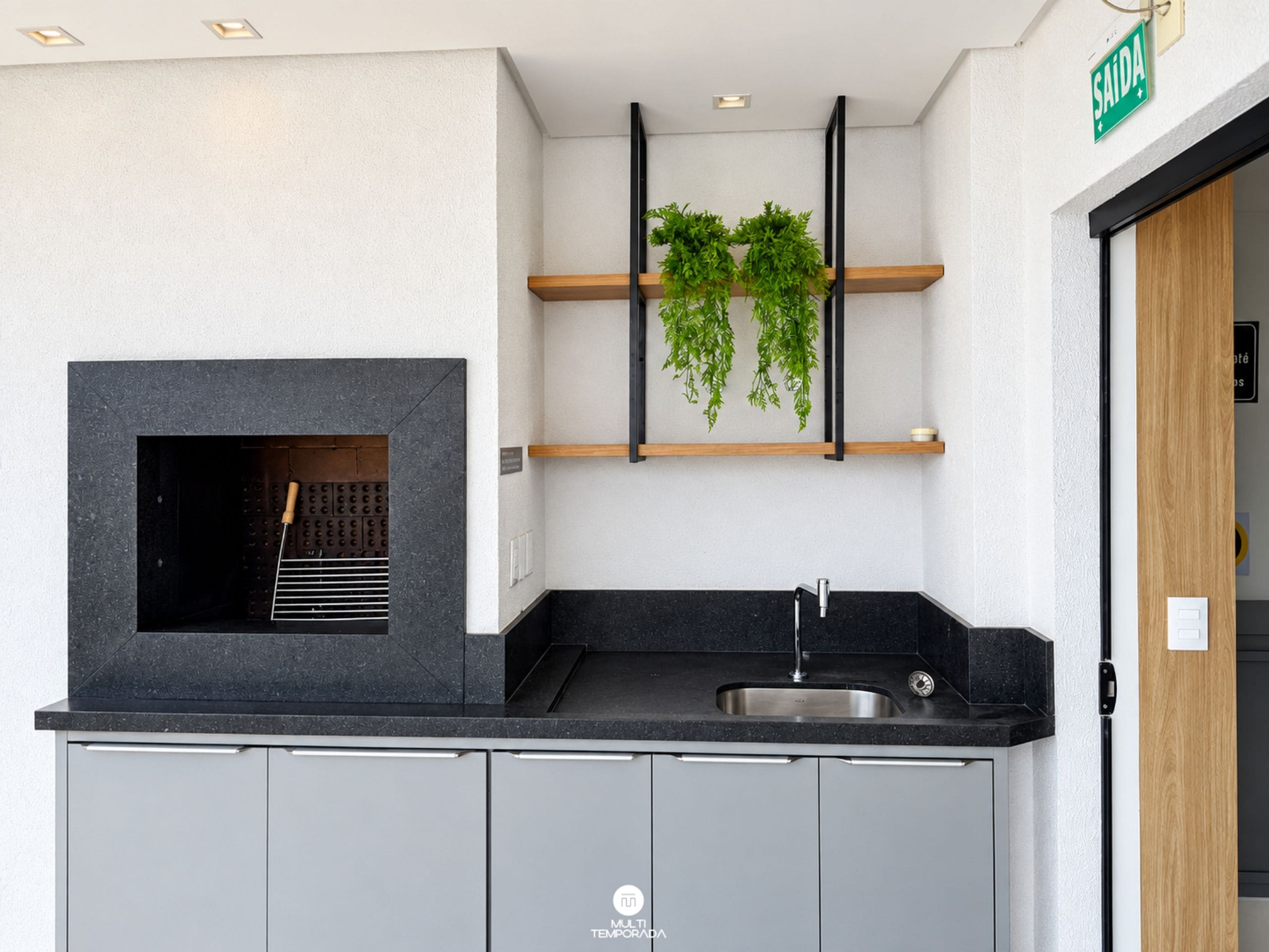 Una cocina moderna con una parrilla integrada, un lavaplatos y una estantería con plantas.