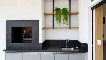 Una cocina moderna con una parrilla integrada, un lavaplatos y una estantería con plantas.