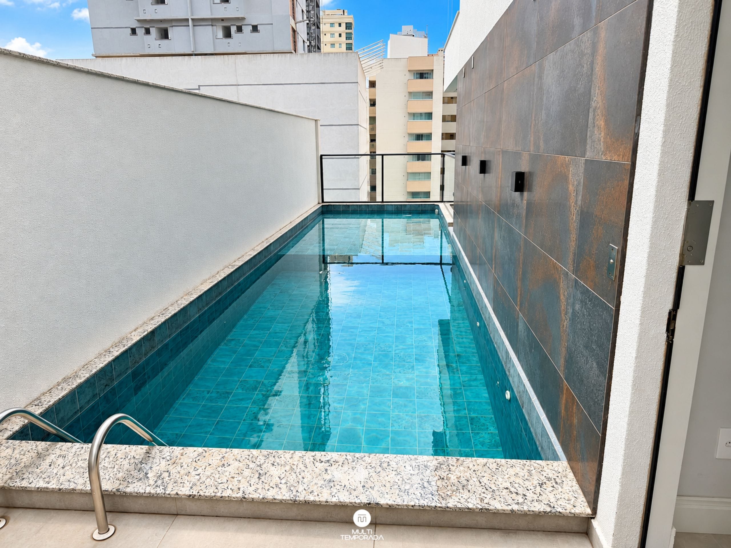 Piscina com água azul cristalina, rodeada por paredes com acabamento texturizado.
