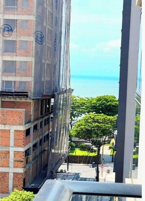 A high-rise building with a view of the sea, construction scaffolding, and a clear sky. - Apartamento Infinity Residence - PB (Porto Belo)