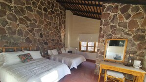 A room with two beds, a desk, a chair, a mirror, and a stone wall. - SS 1A Cabaña rustica frente al malecón de La Paz (La Paz)
