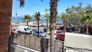 A coastal street with parked cars, palm trees, and a view of the sea. - SS 1A Cabaña rustica frente al malecón de La Paz (La Paz)