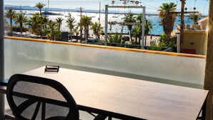 Une chambre dotée d’un bureau et d’une chaise, avec vue sur la mer, et un balcon agrémenté de plantes et d’une balustrade.