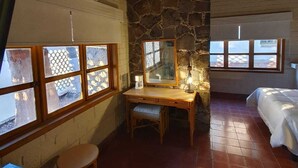 A room with a stone wall, a wooden desk, a chair, a bed, and a window with a view. - SS 4B Cabaña rustica frente al malecón de La Paz (La Paz)