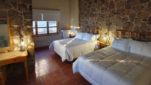 A room with two beds, stone walls, a wooden ceiling, and a window with a view. - SS 4B Cabaña rustica frente al malecón de La Paz (La Paz)