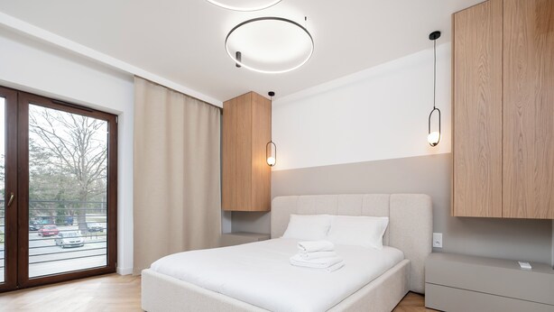 Un dormitorio moderno con una cama grande, un armario de madera y vistas a la calle.