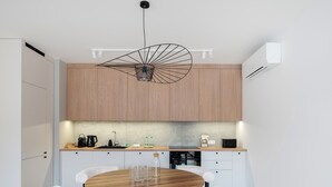 Una cocina moderna con armarios de madera, una mesa redonda de comedor con sillas blancas y una lámpara colgante original.