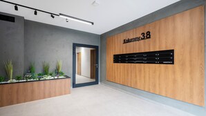 Una zona de recepción moderna con un muro de madera, una puerta de cristal y una exhibición de plantas.