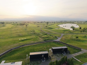 A golf course with bunkers, a pond, and a fenced area with buildings. - Hokkaido ZEN Cabin (Bibai)