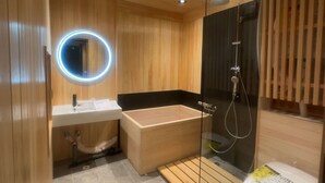Une salle de bain moderne avec un meuble-lavabo en bois, une douche à parois de verre et un miroir rond.