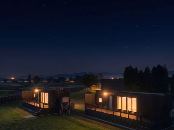 Two modern cabins with large windows, a grassy area, and a night sky with stars. - Hokkaido ZEN Cabin (Bibai)