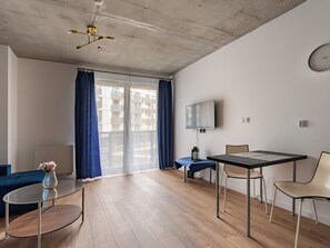 Ein modernes Wohnzimmer mit Glastisch, einer Couch, einem an der Wand montierten Fernseher und einem Deckenventilator.