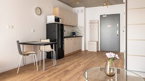 Een moderne keuken met een eethoek, een koelkast, een magnetron en een klok aan de muur.