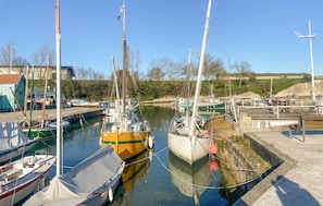 Ein Yachthafen mit vertäuten Booten, ein kleines Gebäude und ein klarer Himmel.