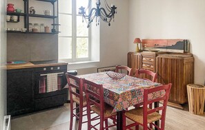 Eine Küche mit Herd, einem Tisch mit Stühlen, einer Kandelaber und einem Schrank mit Schubladen.