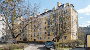 En flervåningsbyggnad med bostäder, en asfalterad uppfart och parkerade bilar.