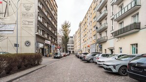 A cobblestone street lined with parked cars and multi-story buildings with balconies. - Gdynia Centrum Coastal Studio (Gdynia)