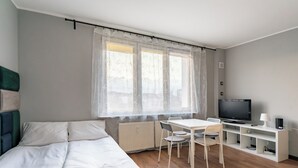 A bedroom with a bed, a desk, a chair, a television, and a radiator. - Gdynia Centrum Coastal Studio (Gdynia)