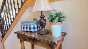 Una mesa de madera con una lámpara, un bolso a cuadros y una planta en maceta en una escalera.
