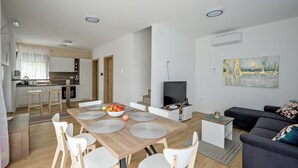Een moderne woonkamer met een eetgedeelte, een keuken en een televisie.