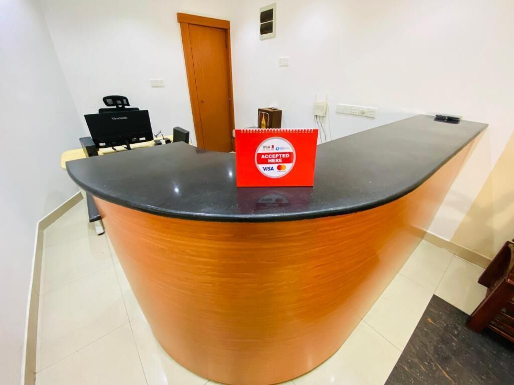 A reception desk with a red 'Accepted Here' sign, a black speaker, and a wooden door in the background.