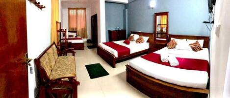 A hotel room with two beds, a sofa, a desk, and a mirror.