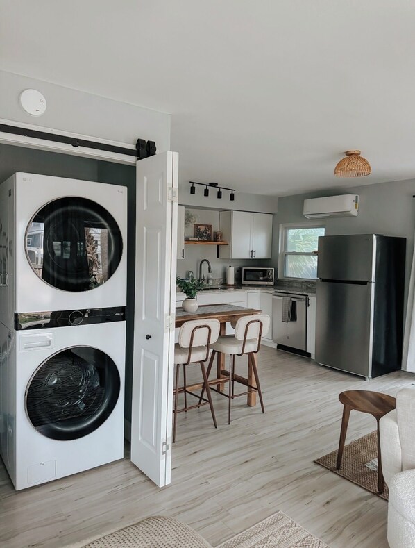 A compact kitchen with a microwave, refrigerator, and a dining area with chairs.