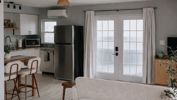 A modern kitchen with a refrigerator, microwave, and dining area with chairs. - Pet Friendly Studio / Walk to Beach & Eats (Panama City Beach)