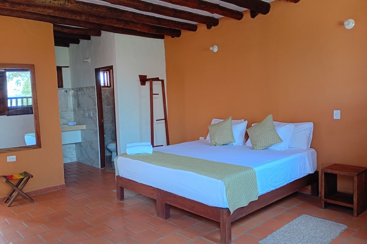 A bedroom with a wooden bed, a bathroom with a marble sink, and a tiled floor.