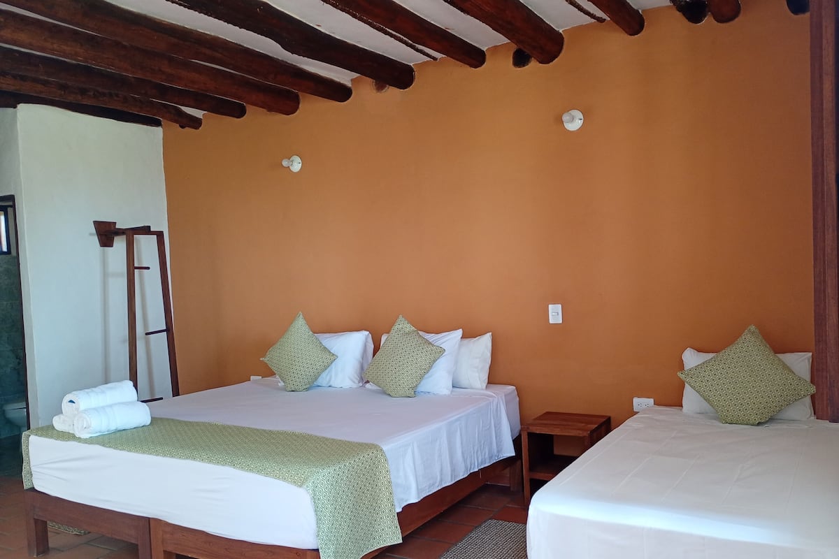 A bedroom with two beds, a wooden ladder, a small wooden nightstand, and a tiled floor.