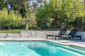 Una piscina con sillas de descanso y un muro de piedra.