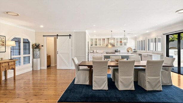 Une cuisine moderne avec des meubles blancs, un îlot central et des luminaires suspendus.
